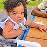 Zahmiyah Frison is registered to the contest to win money with this photo: baby, child, clothing, curly_hair, cute, daylight, fence, greenery, high_chair, outdoor, parenting, park, person, photography, seat, serious_expression, skin, table, text_overlay, toddler