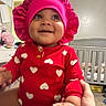 Zahmiyah Frison joined the competition — help win amazing prizes! baby, infant, child, smiling, pink_bonnet, red_shirt, heart_pattern, diaper, hands, nursery, crib, soft_toys, indoor, person, cute, happy, portrait, sitting, support, clothing