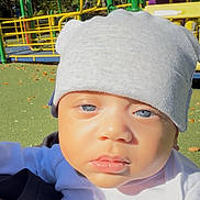 Maverick joined the competition — help win amazing prizes! baby, child, beanie, hat, face, blue_eyes, outdoor, playground, play_equipment, greenery, sunlight, autumn_leaves, curious, infant, closeup, person, clothing, park, daylight, cute