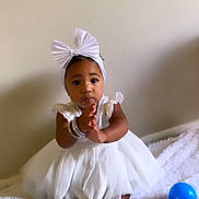 Yaneliz joined the competition — help win amazing prizes! baby, child, white_dress, bow_headband, clapping, sitting, blanket, indoor, toys, colorful_balls, purple_ball, blue_ball, cute, adorable, infant, soft_texture, happy, portrait, young_child, clothing