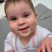 Jovi-May is registered to the contest to win money with this photo: baby, child, smiling, face, pigtails, cute, indoor, couch, hand, clothing, happy, portrait, infant, young_child, skin, person, closeup, expression, pink, white