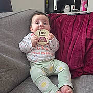 Jovi-May joined the competition — help win amazing prizes! baby, blanket, child, clothing, colorful, couch, cute, expression, face, feet, furniture, head, holding, indoors, infant, pattern, person, sign, sitting, young