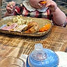 toddler, child, eating, food, plate, carrot, sippy_cup, table, indoor, restaurant, hair_clips, pink, plaid_shirt, baby, cute, messy, meal, wooden_table, glass, person