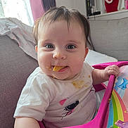 Jovi-May is registered to the contest to win money with this photo: baby, blanket, child, clothing, colorful, couch, face, food, happy, highchair, home, indoor, messy, person, pink_tray, santa_decoration, smiling, snack, toy, window