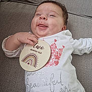 Jovi-May joined the competition — help win amazing prizes! baby, child, couch, cozy, cute, face, hand, happy, indoors, infant, lying_down, person, portrait, rainbow, skin, smiling, text, two_months_old, white_clothing, wooden_sign