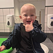 Carson joined the competition — help win amazing prizes! toddler, child, boy, smiling, thumbs_up, jacket, black_shirt, denim_pants, indoor, bathroom, sink, soap_dispenser, tile_wall, countertop, happy, portrait, cute, casual, person, light