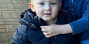 Carson is registered to the contest to win money with this photo: toddler, child, blue_eyes, jacket, pavement, outdoor, sibling, arm, hand, warm_clothing, zipper, person, cute, face, winter_wear, hooded_jacket, standing, smile, young_child, casual
