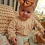baby, child, bow, headwear, bed, blanket, pillow, hands, person, clothing, pattern, indoor, lamp, curtains, soft_lighting, sitting, cute, infant, portrait, home