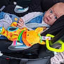 baby, car_seat, plush_toy, giraffe, blue_eyes, denim, sock, blanket, safety_harness, infant, child, cute, toy, clothing, seatbelt, indoor, person, young_child, seat, car_interior
