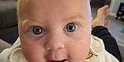 Gracie joined the competition — help win amazing prizes! adult, baby, blue_eyes, blurred_background, close_up, clothing, couch, curious, duck_print, eyes, face, head, home, hoodie, human, indoor, infant, person, skin, smile