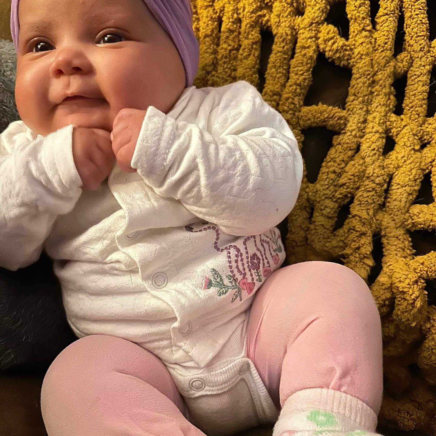 Estella Rose joined the competition — help win amazing prizes! baby, blanket, child, cozy, cute, face, hands, headwrap, indoor, infant, pink, portrait, purple, seated, smiling, socks, soft_lighting, texture, white_clothing, yellow