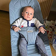 Tobias a rejoint le concours — aidez-le/la à gagner de superbes lots ! baby, bouncer, babybjorn, blue, striped_socks, onesie, indoor, floor, wooden_floor, curious, child, infant, clothing, seat, furniture, person, portrait, hand, face, footwear