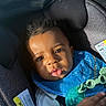 baby, child, car_seat, blue_bib, pacifier, sunlight, face, eyes, hair, clothing, infant, seat_belt, closeup, portrait, expression, cute, indoors, hand, skin, young