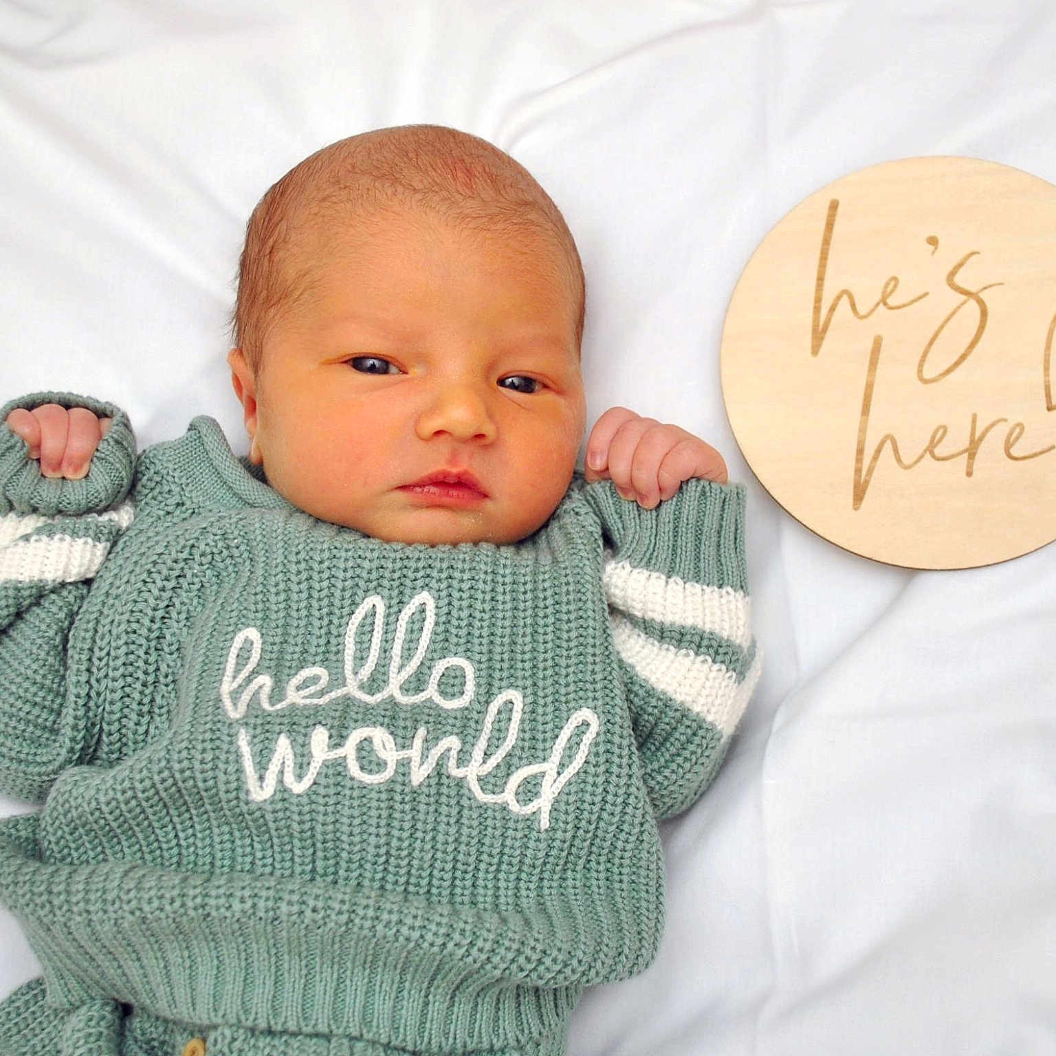 Levi is registered to the contest to win money with this photo: newborn, baby, infant, knitted_sweater, green_sweater, white_blanket, wooden_plaque, text, portrait, cute, face, hand, lying_down, indoor, cozy, celebration, announcement, fresh, small_hands, sleepy