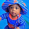 baby, blue, child, closeup, colorful, crab, cute, expression, hat, holding_hands, infant, orange, outdoor, person, playful, portrait, smiling, striped_clothing, sunhat, young
