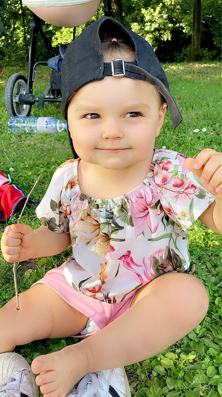 Aya a rejoint le concours — aidez-le/la à gagner de superbes lots ! baby, baby_toddler_clothing, cap, child, facial_expression, finger, fun, grass, hand, happy, headgear, headwear, joy, leisure, people_in_nature, person, pink, plant, recreation, sitting