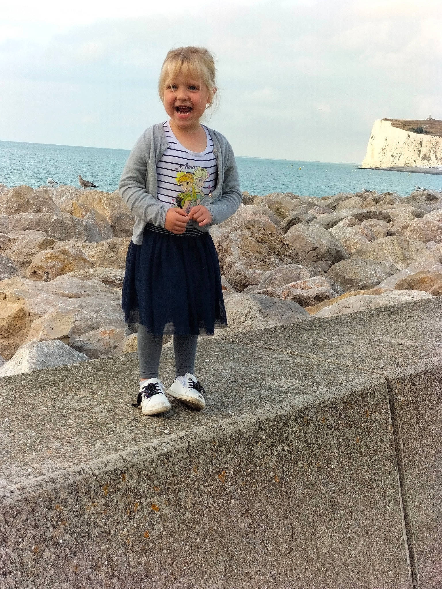 Chloé participe au concours pour gagner de l'argent avec cette photo : asphalt, baby_toddler_clothing, bedrock, cloud, fun, happy, horizon, joy, landscape, leisure, person, recreation, rock, sitting, sky, sleeve, smile, t_shirt, toddler, travel