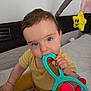 baby, blue_eyes, chewing, child, colorful_toys, crawling_area, curious, cute, face, hand, indoor, infant, playpen, playtime, sitting, smiling_star, soft_toys, toy, yellow_clothing, young_child