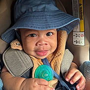 Tamari is registered to the contest to win money with this photo: baby, blanket, blue_hat, car_seat, child, clothing, cute, eyes, face, hand, headwear, indoors, infant, pacifier, person, portrait, seatbelt, skin, smile, young_child