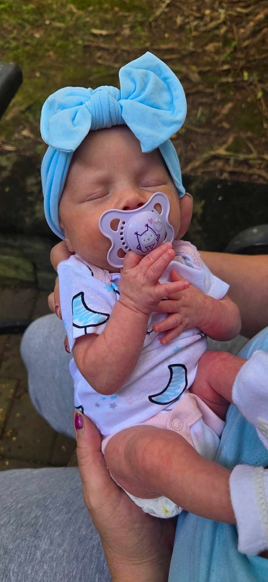 Raelynne is registered to the contest to win money with this photo: baby, infant, pacifier, headband, blue, hands, outdoor, nature, sleeping, clothing, person, cute, newborn, holding, skin, face, peaceful, small, child, toddler