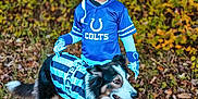 Gunner is registered to the contest to win money with this photo: animal, autumn, blue_jersey, child, costume, dog, fall_foliage, football_helmet, gloves, grass, happy, leaves, nature, outdoor, pet, referee_costume, smiling, sportswear, tongue_out, young_child
