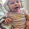 Poppy is registered to the contest to win money with this photo: baby, headphones, onesie, striped_clothing, princess_text, smiling, child, indoor, couch, floral_pattern, hand, face, cute, infant, comfort, light, portrait, happy, seated, casual