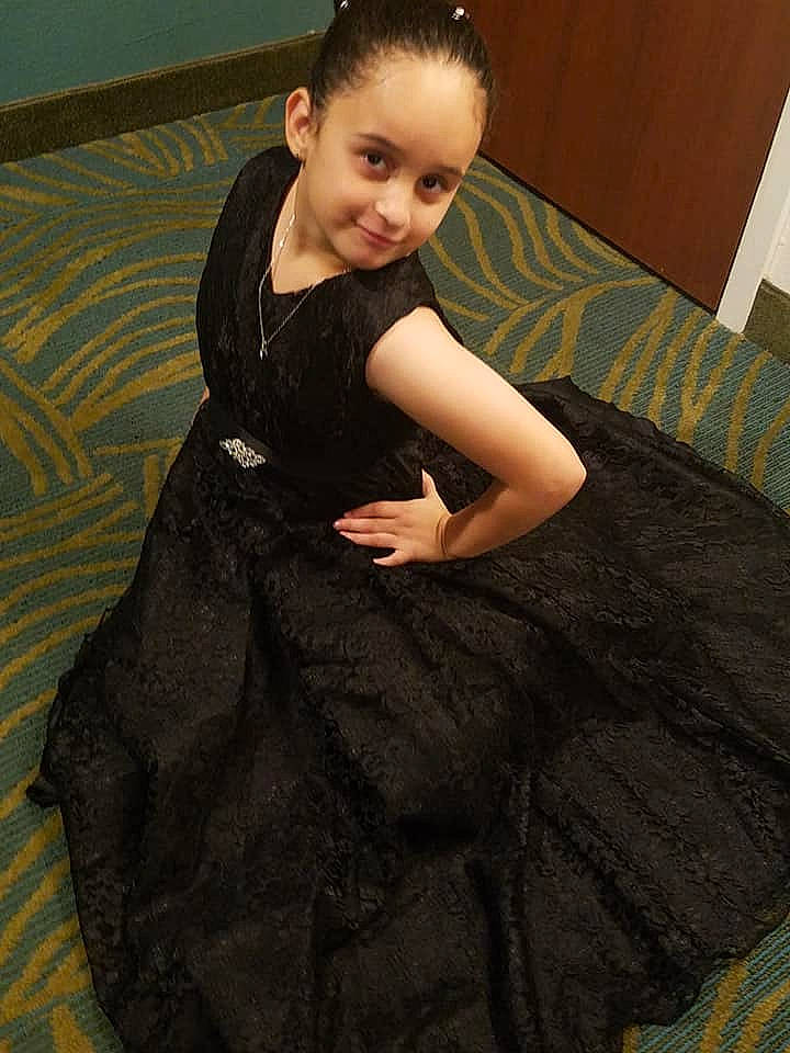 Anabella is registered to the contest to win money with this photo: beauty, black, child, dress, eye, flooring, fun, girl, lady, leg, person, sitting, smile