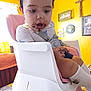Ocean is registered to the contest to win money with this photo: toddler, child, high_chair, messy, food, chocolate, face, expression, indoor, yellow_wall, welcome_sign, cross, shirt, socks, seatbelt, curious, surprised, furniture, home, table