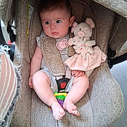 Kelly participe au concours pour gagner de l'argent avec cette photo : baby, car_seat, plush_toy, pacifier, infant, child, soft_toy, seat_belt, fabric, cute, indoor, comfort, pink, expression, skin, foot, hand, toy, sitting, closeup