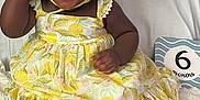 Kayla joined the competition — help win amazing prizes! baby, child, smiling, happy, sitting, dress, hat, indoor, blanket, milestone, sign, feet, cute, infant, portrait, person, fabric, pattern, yellow, celebration