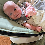 Atlas joined the competition — help win amazing prizes! baby, infant, plush_toy, blanket, baby_seat, indoor, carrying_strap, cute, child, soft_toy, wooden_floor, carpet, person, face, smiling, resting, comfort, toddler, clothing, blanket_pattern