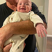 Leonardo is registered to the contest to win money with this photo: adult, arm, baby, casual, child, clothing, dinosaur_pattern, doorway, face, hand, happy, holding, home, indoor, light_switch, onesie, person, portrait, skin, smiling