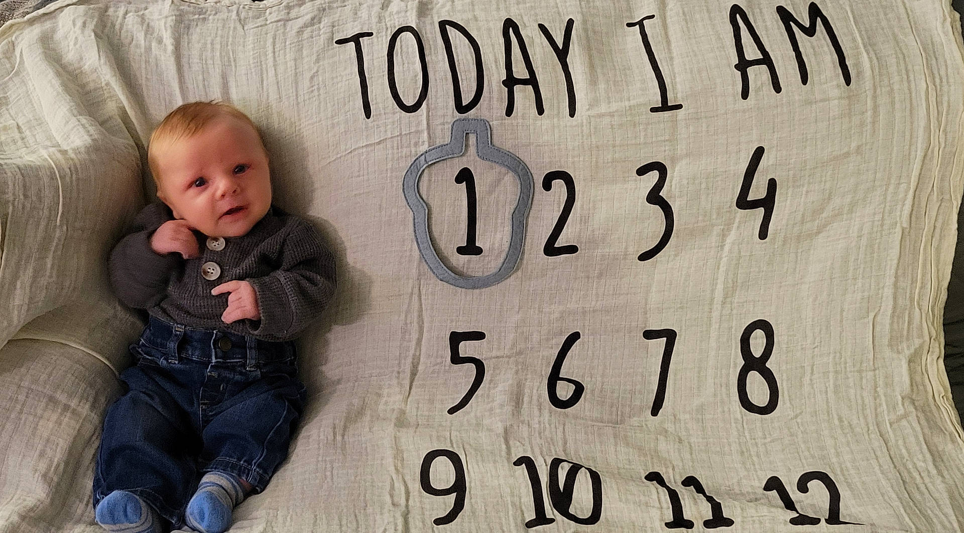 baby, bodypart, clothing, couch, cushion, face, finger, furniture, hand, head, homedecor, jeans, number, pants, person, photography, portrait, sitting, symbol, text