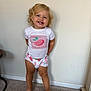 barefoot, blonde_hair, carpet, child, clothing, curly_hair, cute, face, floor, happy, indoor, person, shorts, smiling, standing, toddler, toes, wall, white_shirt, young_child