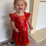 Rendall joined the competition — help win amazing prizes! barefoot, blonde_hair, carpet, child, curly_hair, cute, face, happy, home, indoor, person, playful, portrait, power_cord, red_dress, smiling, standing, toddler, traditional_clothing, wall