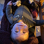 Kayce joined the competition — help win amazing prizes! child, smiling, upside_down, blanket, swing, jacket, nike_logo, face, person, happy, cozy, indoors, warm_light, patterned_blanket, wooden_swing, casual_clothing, young_child, comfort, relaxing, portrait