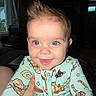 Kayce joined the competition — help win amazing prizes! baby, child, smile, face, blue_eyes, mohawk, onesie, patterned_clothing, indoor, window, hand, happy, cute, infant, portrait, cozy, light, person, apparel, young