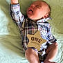 Felix is registered to the contest to win money with this photo: baby, infant, plaid_clothing, onesie, star_sign, green_blanket, sleeping, raised_arm, cute, newborn, soft_fabric, indoor, skin, foot, hand, head, peaceful, lying_down, one_month, celebration