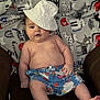 baby, child, hat, bucket_hat, shorts, blanket, cat_pattern, indoor, sitting, cute, chubby, relaxed, curious, skin, foot, hand, clothing, infant, portrait, young
