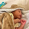 baby, sleeping, blanket, soft_texture, infant, cozy, resting, hand, face, peaceful, indoors, yellow_clothing, baby_wipes, fabric, close_up, skin, cute, newborn, toddler, comfort