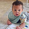 baby, child, infant, play_mat, bib, camo_shirt, curly_hair, indoor, floor, expression, looking, hands, colorful, soft, cozy, person, young, cute, portrait, toddler