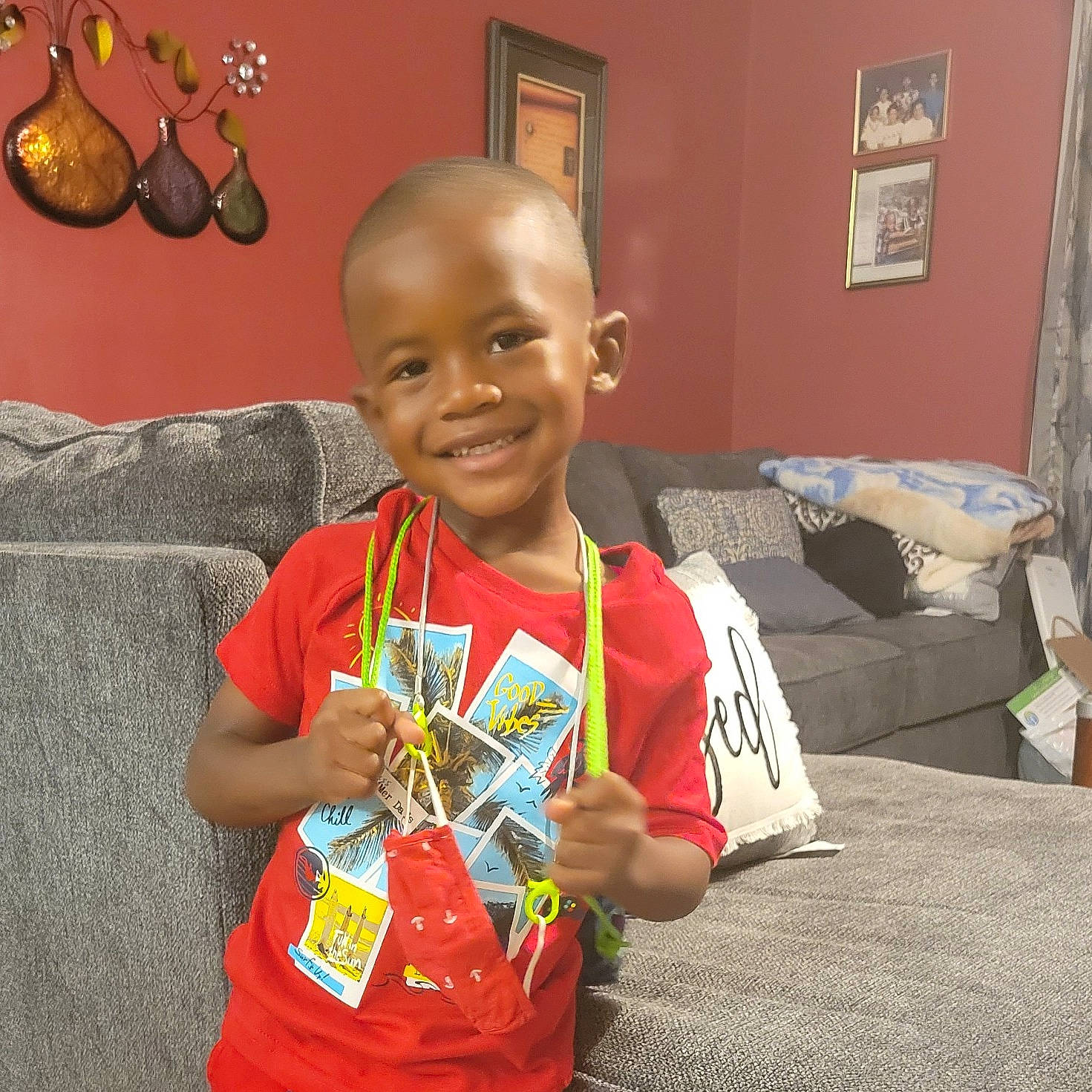Patrick is registered to the contest to win money with this photo: baby, child, comfort, couch, curtain, event, flooring, fun, happy, holiday, joy, living_room, person, picture_frame, room, sitting, sleeve, smile, studio_couch, t_shirt