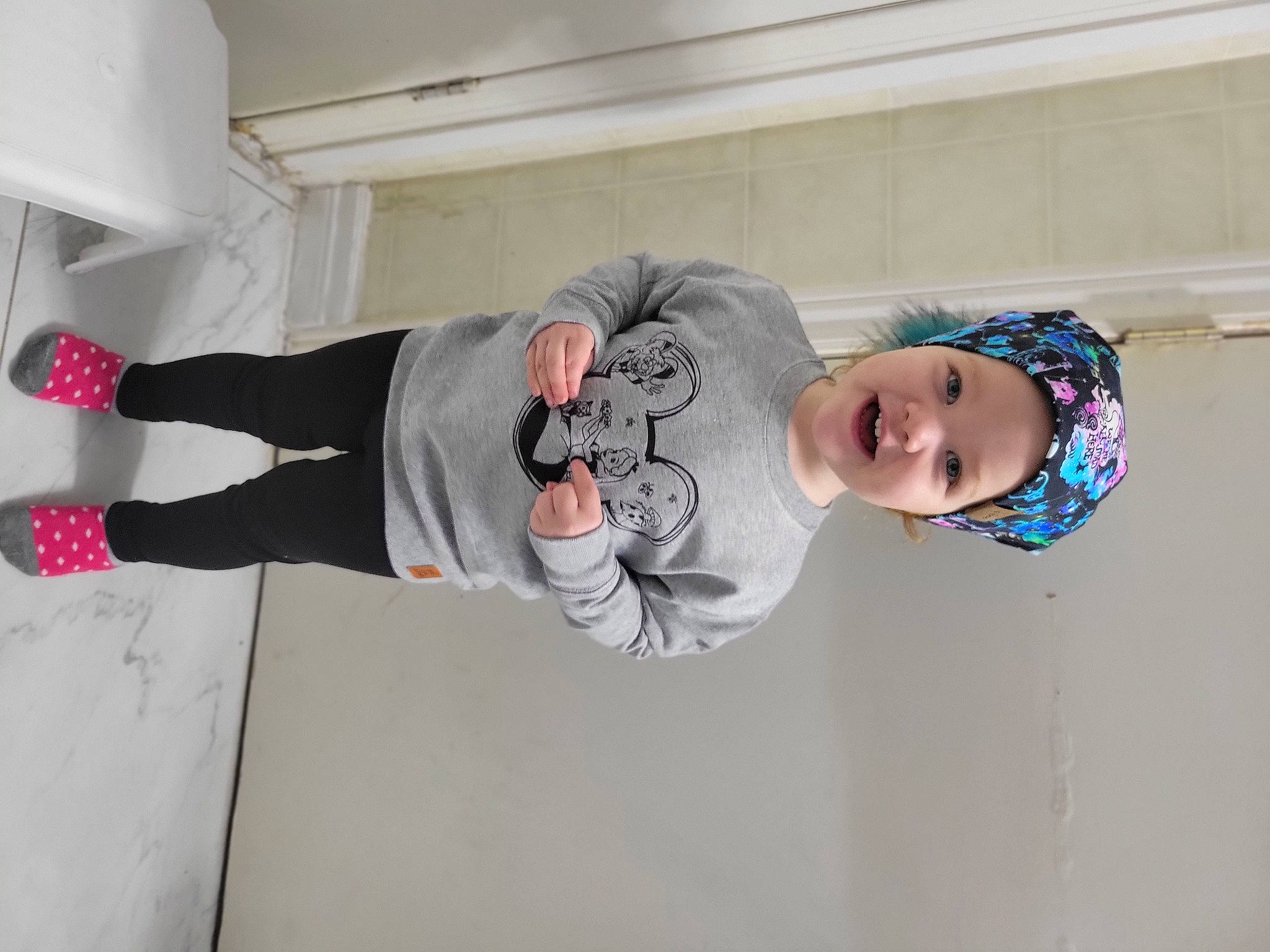 Esme joined the competition — help win amazing prizes! active_pants, baby_toddler_clothing, child, flooring, fun, hat, headwear, knee, outdoor_shoe, person, plant, sleeve, smile, sweatpant, t_shirt, toddler, walking_shoe, wood