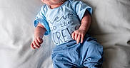 Charles is registered to the contest to win money with this photo: baby, infant, blue_clothing, hat, blanket, lying_down, newborn, cute, portrait, soft_texture, cozy, baby_garment, socks, white_background, small_hands, baby_face, indoors, child, resting, sleepwear
