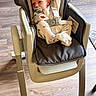 baby, high_chair, pacifier, onesie, indoor, child, flooring, wood_floor, seat_belt, infant, baby_clothes, baby_seat, furniture, baby_girl, baby_boy, baby_face, baby_hands, baby_feet, home_interior, child_safety
