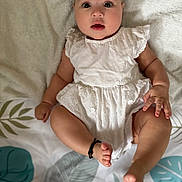 Cynthia joined the competition — help win amazing prizes! baby, barefoot, blanket, child, curious, cute, expression, foot, hand, indoors, infant, leaf_pattern, lying_down, portrait, relaxed, skin, small, soft_texture, white_dress, young