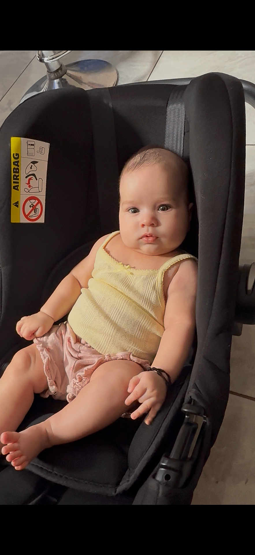 Cynthia joined the competition — help win amazing prizes! baby, black_car_seat, car_seat, child, cute, feet, floor_tiles, head, indoors, infant, legs, person, pink_shorts, portrait, seat_belt, serious_expression, sitting, skin, yellow_top, young_child
