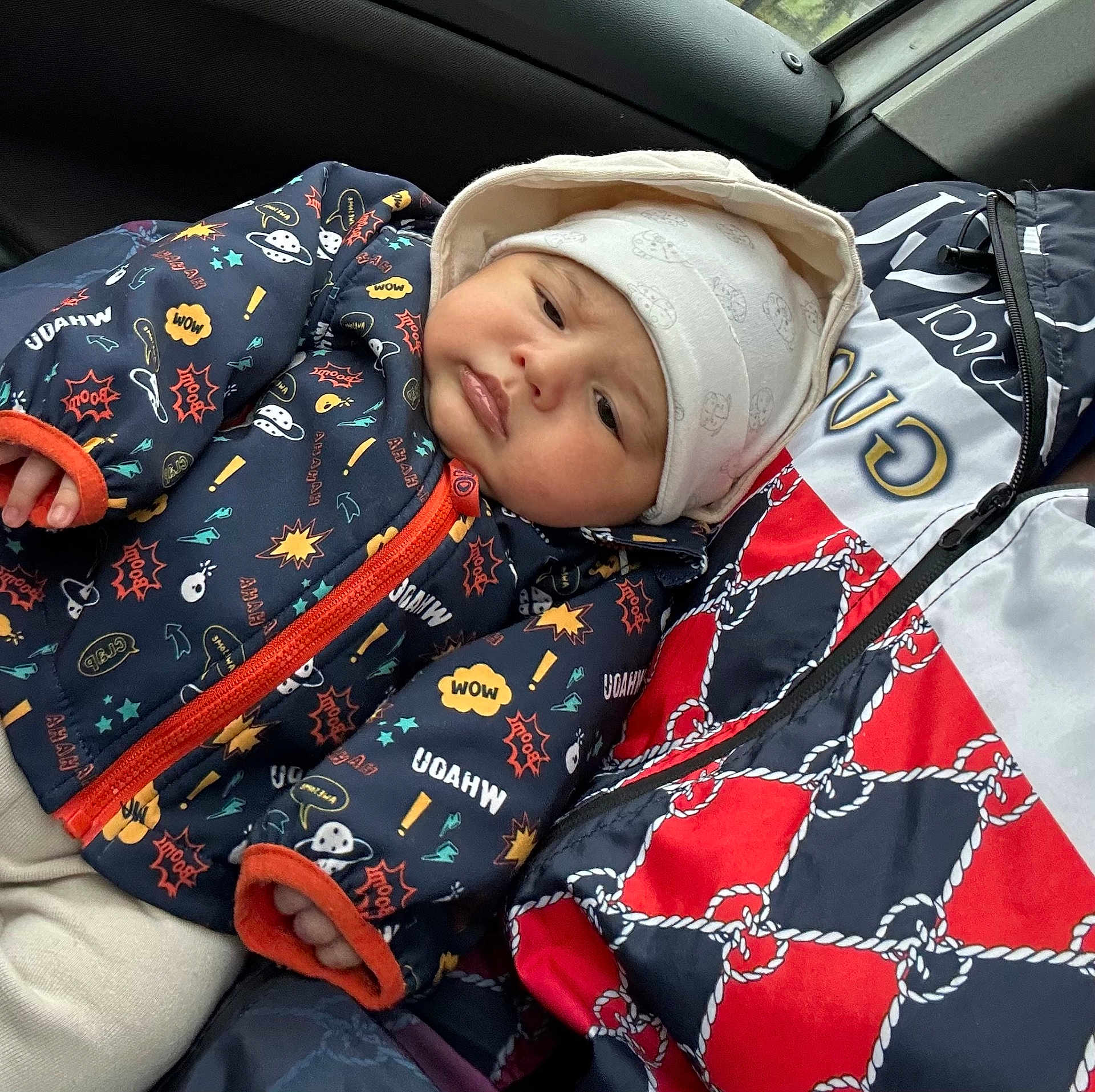 Adonys participe au concours pour gagner de l'argent avec cette photo : baby, child, jacket, hat, patterned_clothing, car_interior, person, warm_clothes, colorful, seated, portrait, infant, cute, cozy, bundle, seat, winter_wear, baby_face, adult, closeup