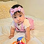 Marbella Esparza is registered to the contest to win money with this photo: baby, child, infant, headband, pink_clothing, toy, bed, white_bedspread, crawling, colorful_toy, pillow, indoor, cute, person, face, hand, play, room, young_child, soft_toy
