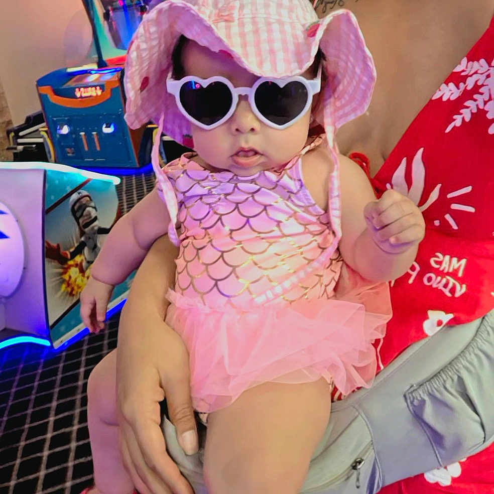 Marbella Esparza is registered to the contest to win money with this photo: accessory, adult, arcade, baby, child, cute, dress, fashion, floor, gaming_machine, hand, hat, holding, indoor, pattern, person, pink, red_dress, sunglasses, tutu